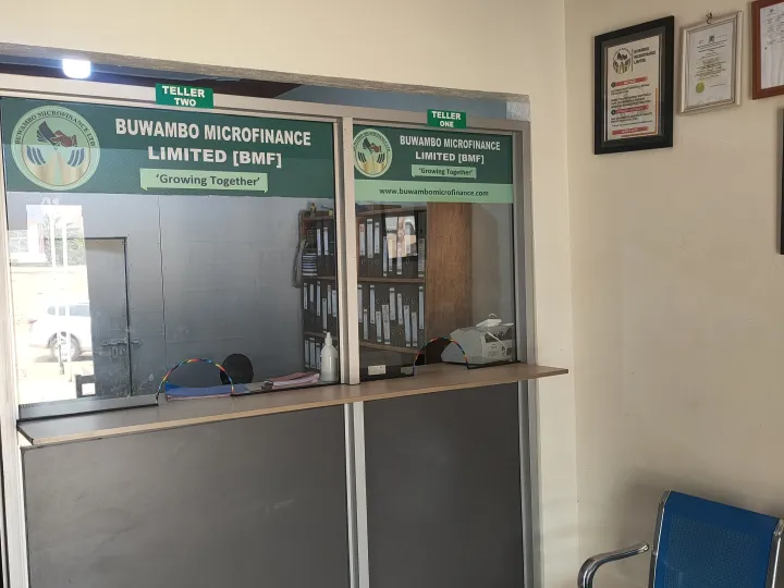 A Buwambo Microfinance customer service counter with company signage
